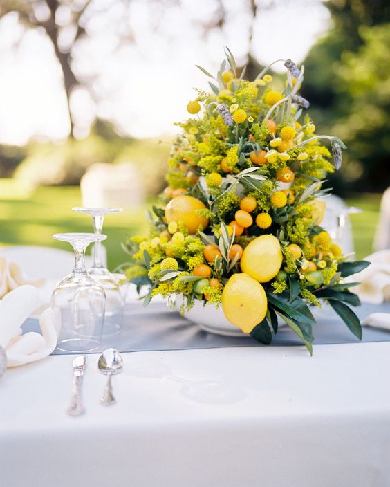 a lovely wedding centerpiece of mimosa blooms, lemons and kumquats and some foliage is a lovely idea of a summer decoration