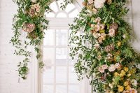 a lush and beautiful floral and greenery indoor wedding backdrop is a lovely and chic idea for a refined space