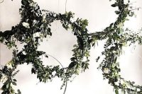 a lush wedding backdrop of embroidery hoops with white blooms and greenery is a chic and lovely idea to rock