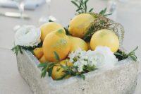 a modern wedding centerpiece of a concrete box, white blooms and greenery and lemons is a catchy and out of the box idea
