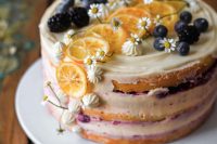 a naked lemon wedding cake topped with blueberries, lemon slices, meringues, white blooms is a lovely idea for a summer wedding