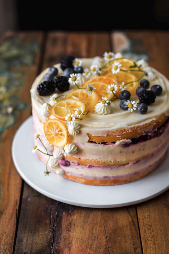 a naked lemon wedding cake topped with blueberries, lemon slices, meringues, white blooms is a lovely idea for a summer wedding