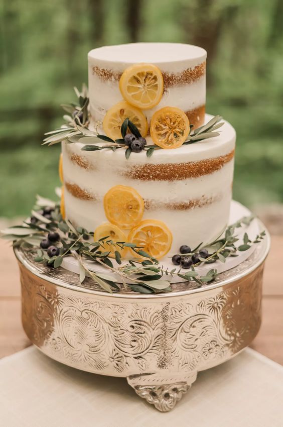a naked wedding cake with herbs, berries and lemon slices is an amazing idea for a spring or summer wedding