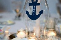 a nautical wedding centerpiece of a large vase with an anchor and a candle, candles around, seashells is a lovely idea for a nautical wedding