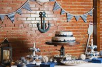 a nautical wedding dessert table with a striped banner, rope balls, a striped banner, anchor and candle lanterns