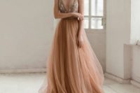 a peachy pink wedding dress with a fitting floral embroidery bodice on spaghetti straps and a layered tulle skirt with a train