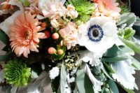 a pretty wedding bouquet of white anemones, coral gerberas, berries, greenery and pale leaves is amazing