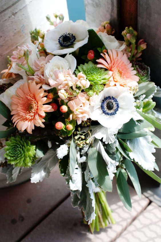 a pretty wedding bouquet of white anemones, coral gerberas, berries, greenery and pale leaves is amazing