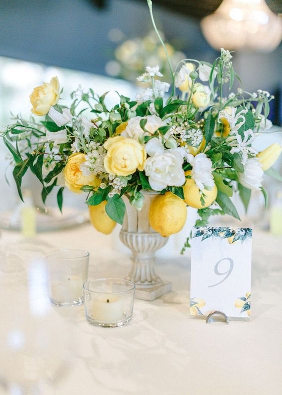 a refined neutral and bold wedding centerpiece of vintage urns, white and yellow blooms, greenery and a cool table number is awesome