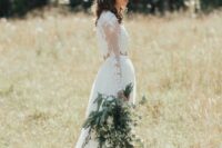 a romantic spring boho bride wearing a lace long sleeve crop top, a flowy skirt with a train, a white flower and greenery crown