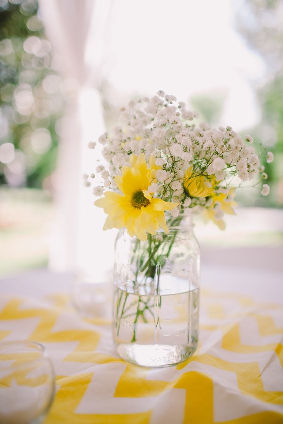 a rustic wedding centerpiece of a jar with baby's breath and yellow gerberas is a lovely and bold idea for a wedding