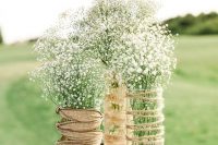 a rustic wedding centerpiece of vases wrapped with twine and burlap, with baby’s breath is a lovely idea for a farmhouse wedding