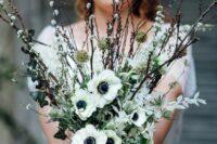 a simple white spring wedding bouquet of white anemones, willow and greenery is amazing for a boho bride and not only
