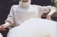 a slouchy chunky off-white turtleneck sweater over a princess-style wedding gown and statement earrings
