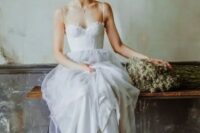 a spaghetti strap gown with a corset bodice and a tulle skirt, an updo with with flowers create a delicate boho spring bridal look