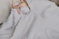 a strapless A-line wedding dress fully covered with feathers, with an embellished sash and a train
