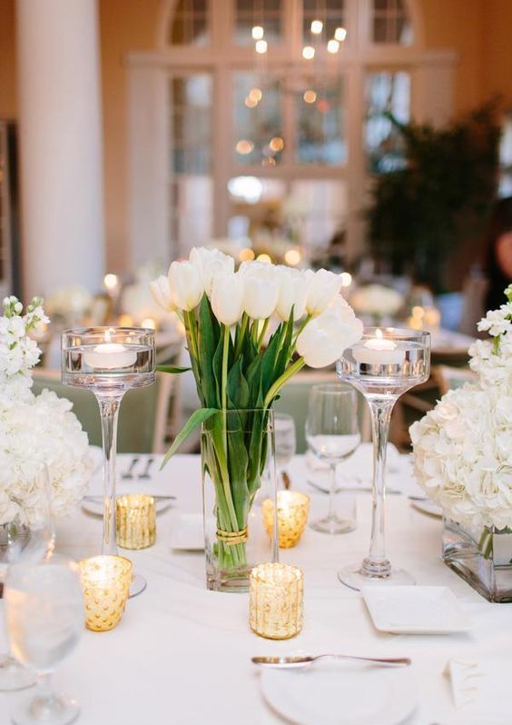 a stylish cluster wedding centerpiece of white hydrangeas, tulips and candles around is an elegant and chic idea to rock