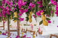 a super colorful wedding tablescape with a greenery, bougainvillea and lemon table runner and a matching overhead installation
