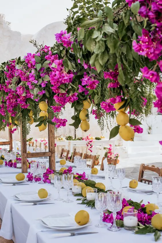 a super colorful wedding tablescape with a greenery, bougainvillea and lemon table runner and a matching overhead installation