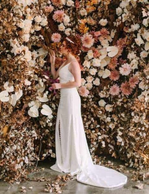 a super lush and refined wedding backdrop of pink, blush and neutral blooms, dried leaves and foliage is a beautiful idea