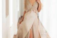 a tan wedding dress with a tulle covered bodice and sheer sleeves, a depe V-neckline and a silk skirt with sheer tulle plus a train