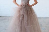 a taupe wedding dress with a layered tulle skirt with fabric blooms and a lace fitting bodice on spaghetti straps
