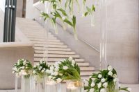a unique wedding altar composed of an acrylic wedding arch with white tulips and white tulip arrangements plus floating candles