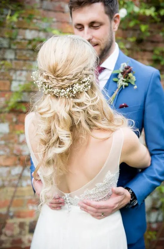 a wavy half updo with a double braided halo and baby's breath looks sweet