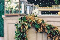 a wedding bar decorated with a lush magnolia leaf garland is a cool idea to spruce up your space