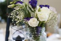 a wedding centerpiece of a jar with twine, with white and bright blue blooms, baby’s breath is a lovely idea to try for a rustic wedding