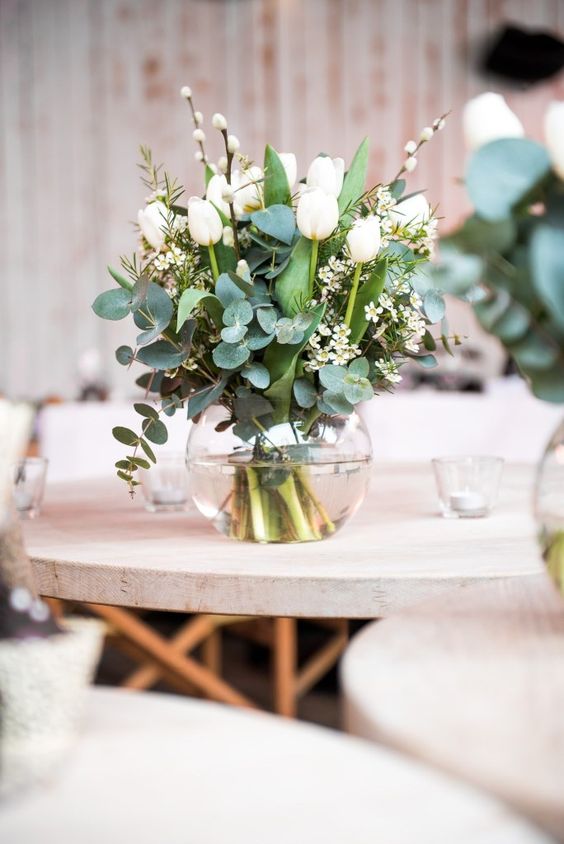 a wedding centerpiece of eucalyptus, white tulips, waxflower and willow is a lovely idea for a spring wedding