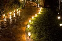 a wedding path illuminated with large bulbs and a gate accented with lights and white blooms look magical in the dark