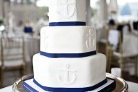 a white and navy hexagon-shaped wedding cake with anchors is a stylish idea for a seaside or nautical wedding