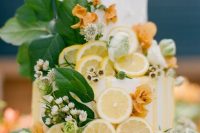 a white buttercream wedding cake covered with cut lemons, rust and white blooms and foliage is a lovely idea for summer