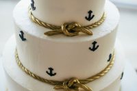 a white buttercream wedding cake with navy anchors and edible gold rope is a stylish idea for a modern nautical wedding
