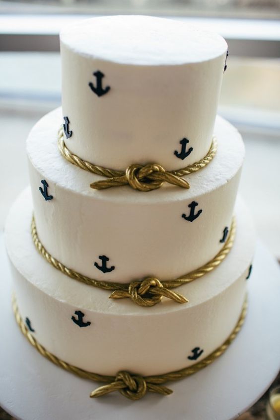 a white buttercream wedding cake with navy anchors and edible gold rope is a stylish idea for a modern nautical wedding