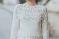 a white patterned cropped sweater with cropped sleeves and a pleated satin skirt