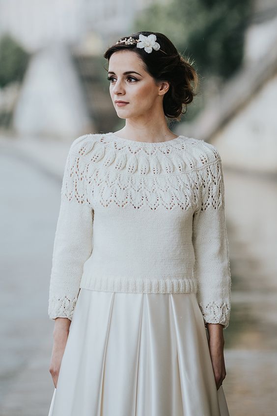 a white patterned cropped sweater with cropped sleeves and a pleated satin skirt