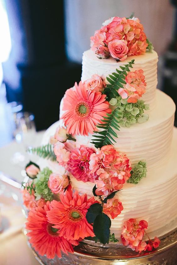 a white textural buttercream wedding cake with bold coral hydrangeas and gerberas, greeneyr for a bright summer wedding