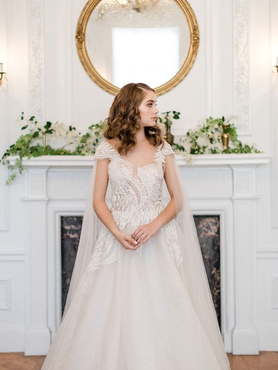 an angel wing wedding dress with a lace bodice and sleeves plus a full skirt and a sheer capelet for a wow look
