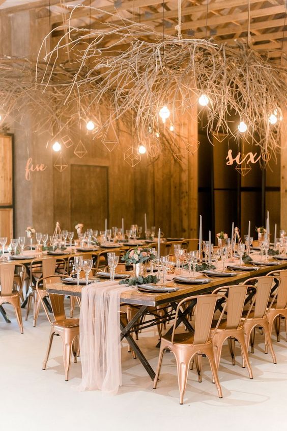 an industrial wedding reception space with branches and himmeli ornaments, with bulbs over the tables to make the room eye-catchy