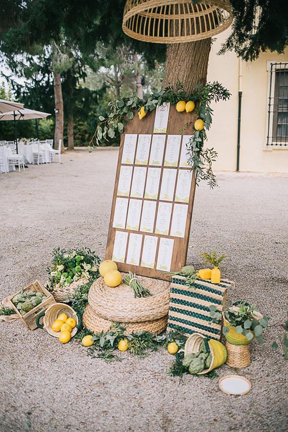 beautiful Italian style wedding decor with jute poufs, a seating chart with greenery and lemons, crates and baskets with lemons