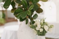 chic and elegant wedding centerpiece of two white vases with magnolia leaves and white blooms