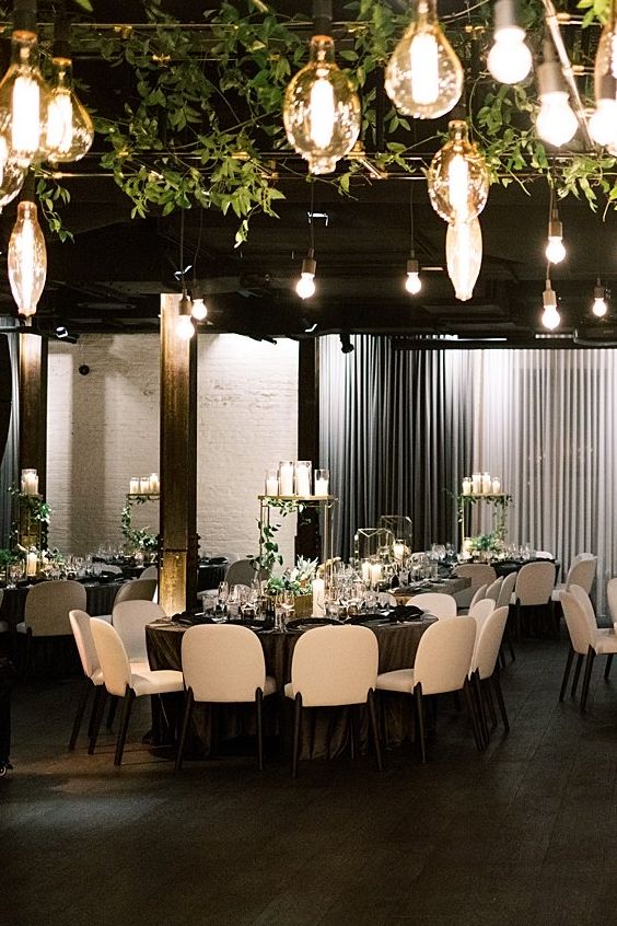 greenery and bulbs hanging over the reception space is a very chic idea for a refined and luxurious wedding reception space