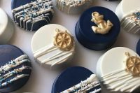 lovely navy and white individual wedding cakes decorated with steerign wheels, anchors and confetti are amazing for a nautical wedding