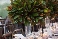 tall wedding centerpieces of clear glass vases and lush magnolia leaves is a cool idea to skip florals
