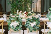 the couple’s chairs decorated with magnolia leaf wreaths and calligrpahy is a cool idea for a southern wedding