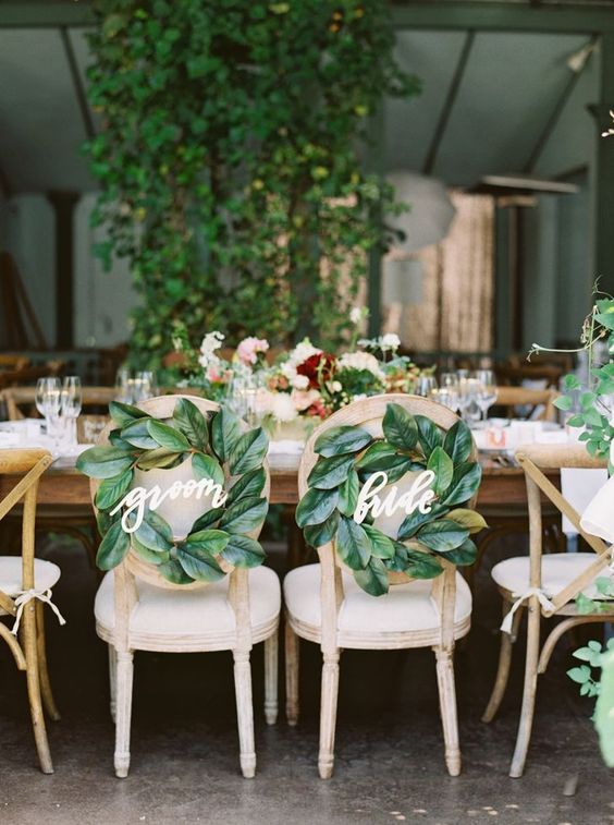 the couple's chairs decorated with magnolia leaf wreaths and calligrpahy is a cool idea for a southern wedding