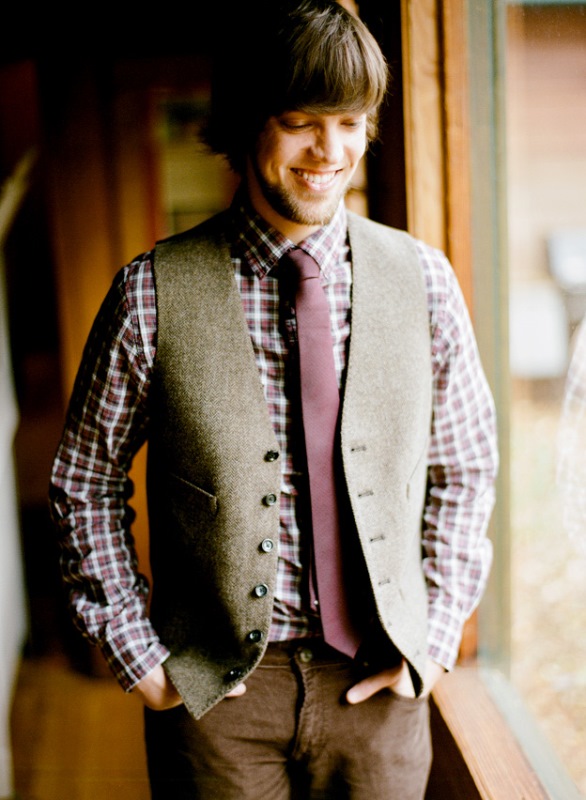 a very relaxed rustic groom's look with brown pants, a plaid shirt, a purple tie and a grey waistcoat