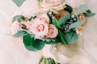 a delicate blush wedding bouquet of roses, astilbe, greenery and berries is a lovely and subtle wedding bouquet idea